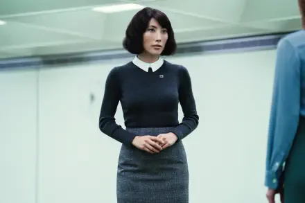 A still from the TV show Severance, featuring Dichen Lachman. The image showcases her poised in a modern, minimalist setting, emphasizing her stylish attire.