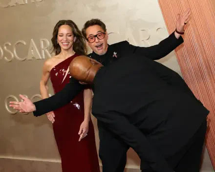 Samuel L. Jackson playfully leans down while Robert Downey Jr. and Susan Downey pose joyfully, capturing a fun moment at the Academy Awards (Oscars) celebration.