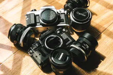 Vintage Canon cameras and lenses arranged on a wooden surface, captured in sharp 4K Ultra HD quality for a striking man-made PC desktop wallpaper.