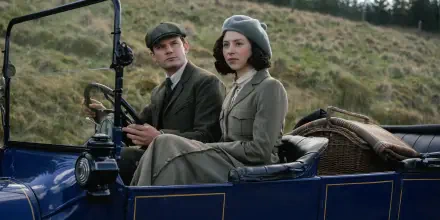 HD desktop wallpaper featuring a scene from the TV show Outlander: Blood of My Blood, depicting two characters dressed in period attire seated in a vintage car.