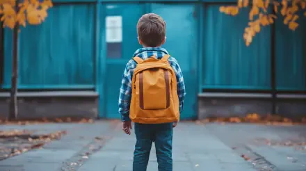 Back to school, first day of school: child with orange backpack facing a blue gate on a leaf-strewn sidewalk — 4K Ultra HD PC desktop wallpaper background.