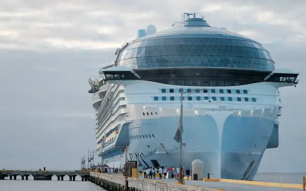 A large Royal Caribbean cruise ship is docked at a pier, showcasing its modern design against a cloudy sky. This 4K Ultra HD image serves as a vibrant desktop wallpaper.