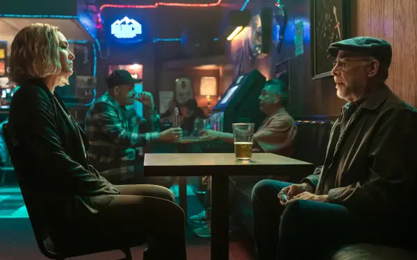 A 4K Ultra HD wallpaper featuring scenes from The Accountant 2, showcasing J.K. Simmons and Daniella Pineda in a bar setting, with a vibrant ambiance and background characters.