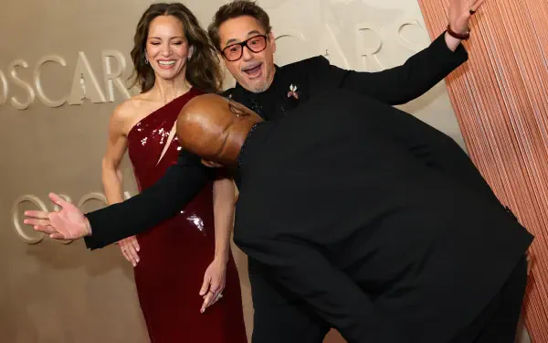 Samuel L. Jackson playfully leans down while Robert Downey Jr. and Susan Downey pose joyfully, capturing a fun moment at the Academy Awards (Oscars) celebration.