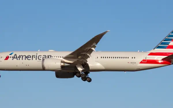A high-resolution image of an American Airlines airplane in flight against a clear blue sky, showcasing its sleek design and vibrant tail colors.