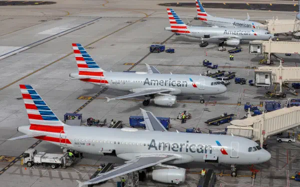 Three American Airlines airplanes are parked at an airport terminal, showcasing a busy scene in a 4K Ultra HD PC desktop wallpaper. Airport staff and equipment are visible nearby.