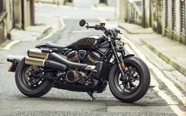 A sleek Harley-Davidson Sportster parked on a quiet street, showcasing its powerful design and chrome accents. This 4K Ultra HD wallpaper captures the bike's striking features.