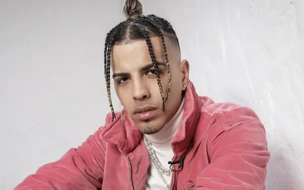 HD PC desktop wallpaper featuring a close-up of music artist Rauw Alejandro wearing a pink jacket against a light background.