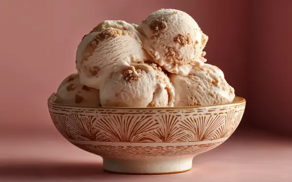 A bowl of creamy ice cream scoops with a textured pattern sits against a soft pink background, captured in stunning 4K Ultra HD as a comforting food desktop wallpaper.