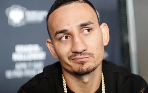 HD PC desktop wallpaper featuring UFC fighter Max Holloway with a thoughtful expression against a blurred event backdrop.