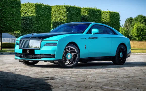 Cyan Rolls-Royce Black Badge Spectre luxury car parked on a stone driveway, rendered as a 4K Ultra HD PC desktop wallpaper with manicured hedges and a clear blue sky background