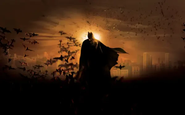 Batman Begins 4K Ultra HD PC Desktop Wallpaper and Background - silhouetted Batman stands amid a swirl of bats against a fiery orange city skyline.
