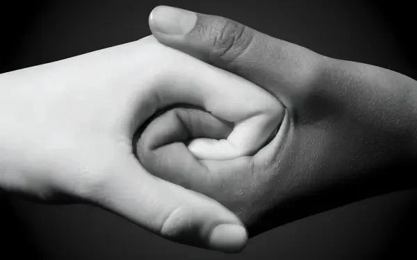 Black-and-white HD PC desktop wallpaper showing two hands clasped in a gentle handshake, symbolizing togetherness, family and friends.