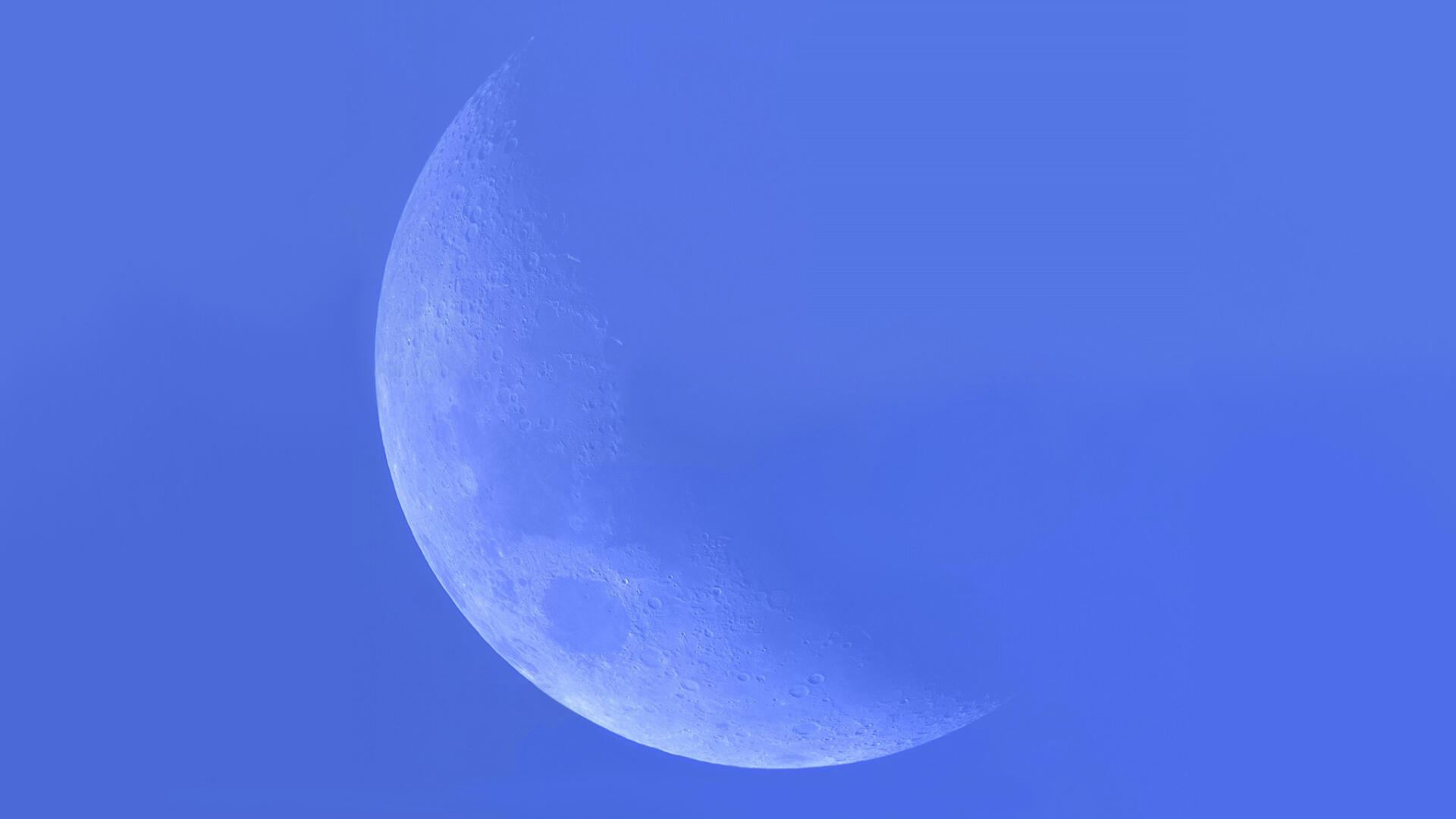 Crescent pale-blue planet floating on a smooth blue field, HD PC desktop wallpaper and background.