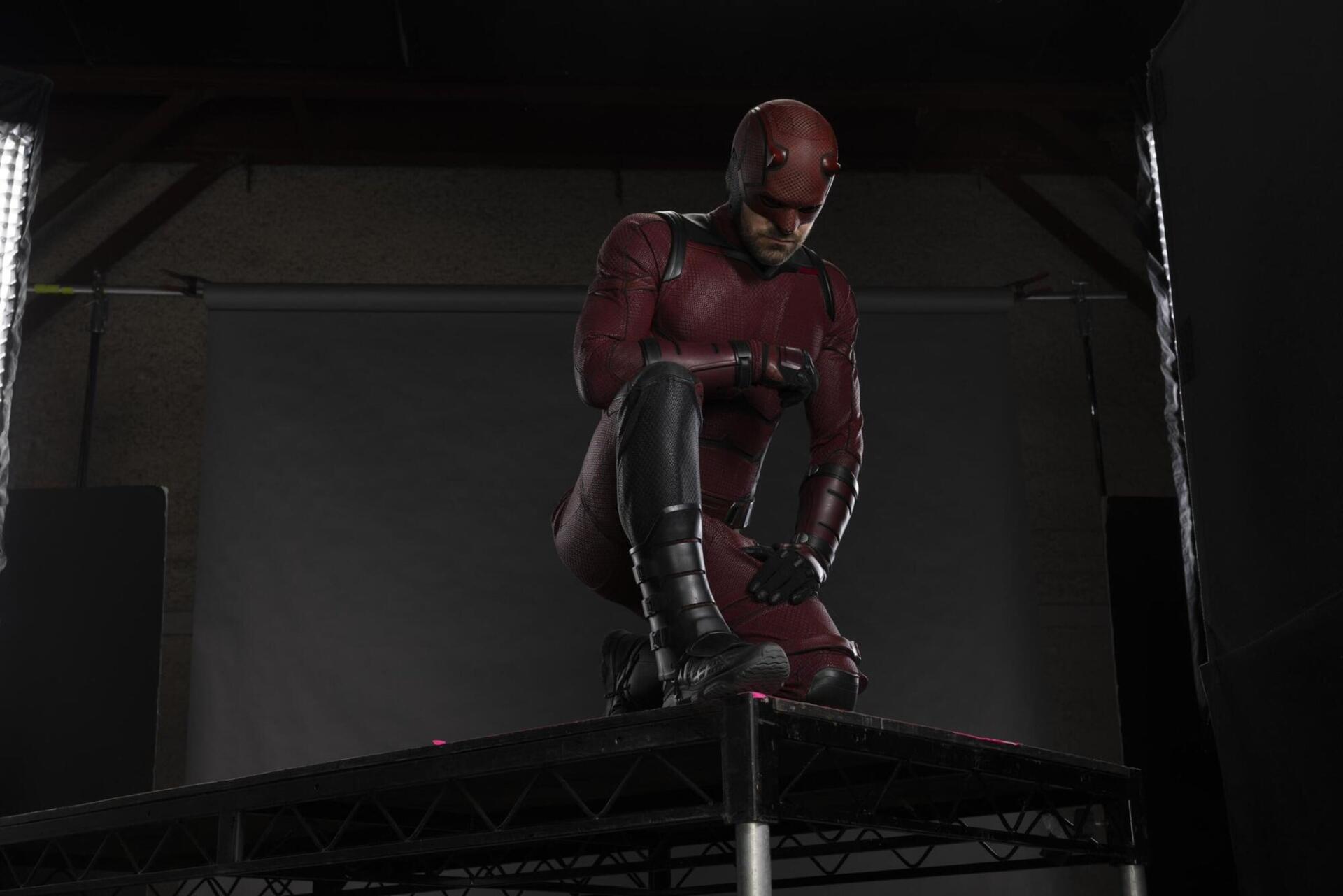 Daredevil: Born Again TV show HD PC desktop wallpaper — Daredevil in red suit kneeling on a rooftop under studio lights against a dark backdrop.