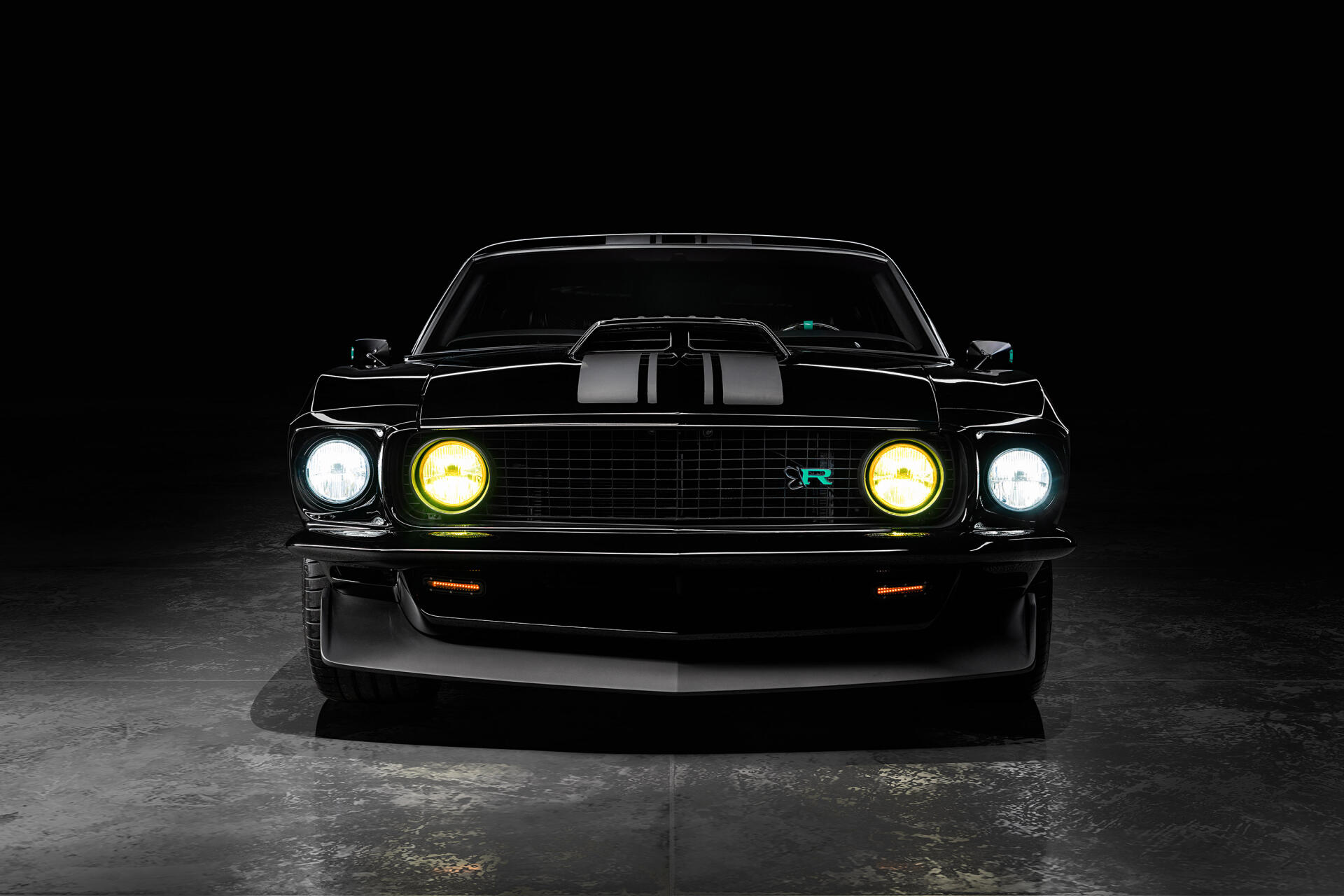 Front view of a black 1969 Ford Mustang Mach 1 with dual hood stripes and glowing headlights, presented as a 2K Quad HD PC desktop wallpaper.
