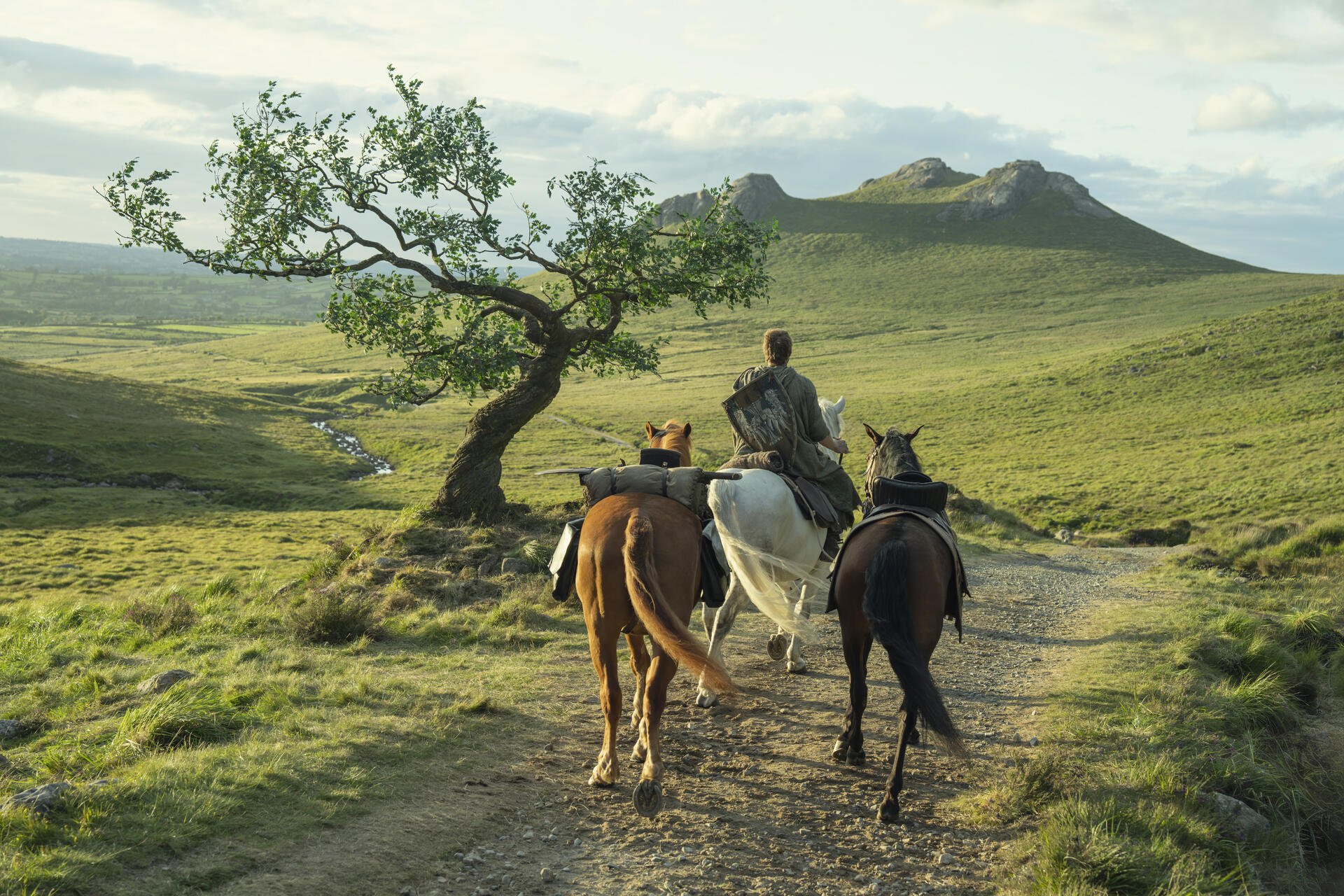 HD PC wallpaper of TV show A Knight of the Seven Kingdoms: three riders on horseback crossing a grassy field toward distant hills, evoking adventure.