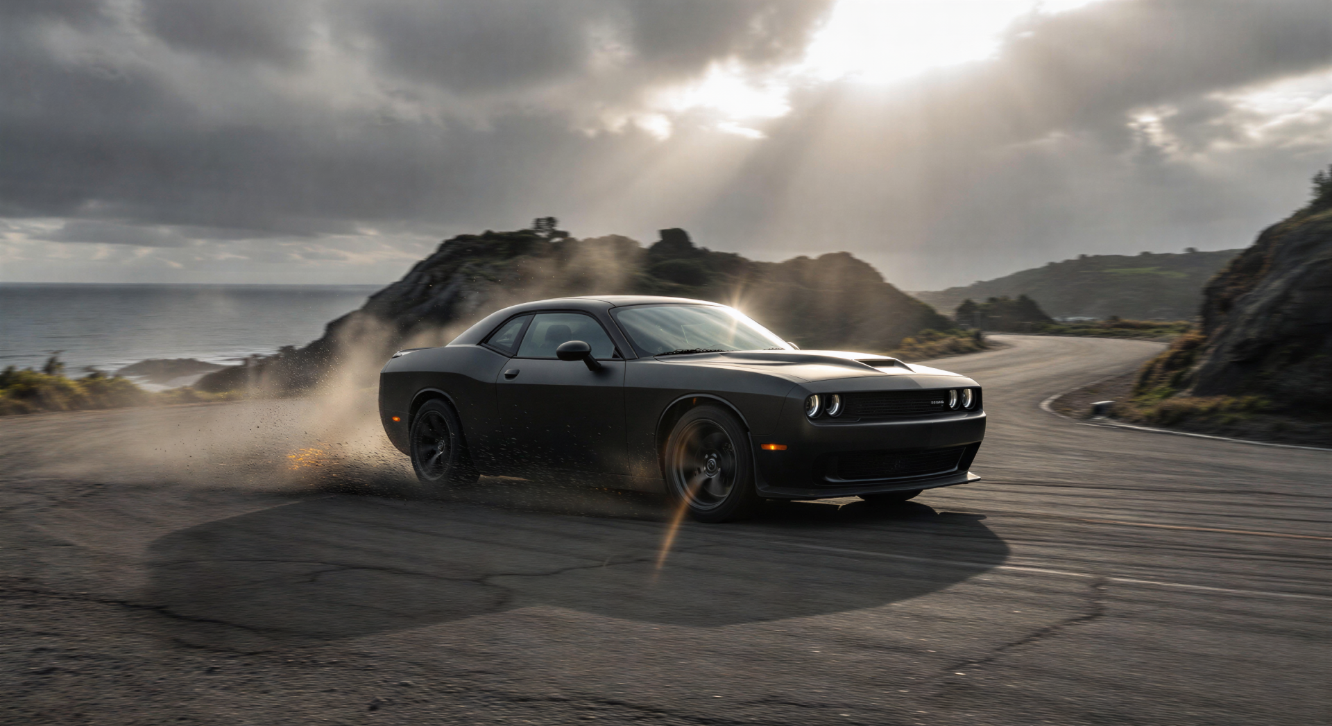 Black Dodge Challenger drifting on a coastal road, kicking up smoke beneath dramatic clouds — 2K Quad HD PC desktop wallpaper/background.
