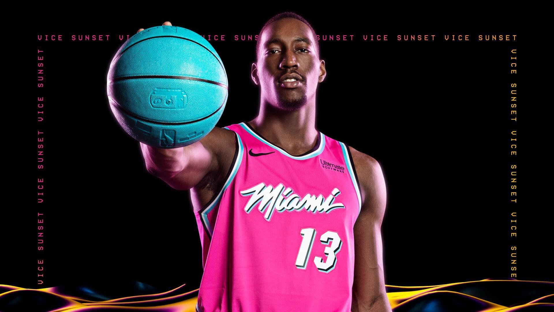 NBA basketball player in a pink Miami Heat jersey holding a teal basketball toward the camera against a dark, stylized HD desktop wallpaper background.