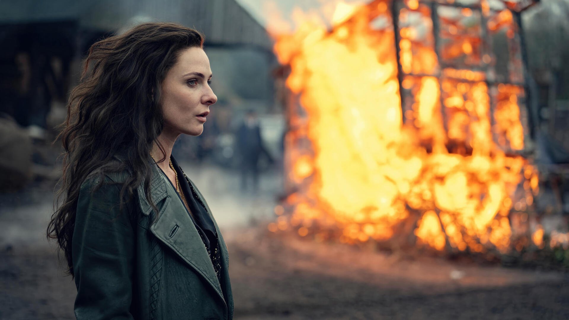Peaky Blinders: The Immortal Man 8K Ultra HD PC desktop wallpaper and background — woman in coat watches a wooden cart blaze on a smoky street, tense period-drama atmosphere.
