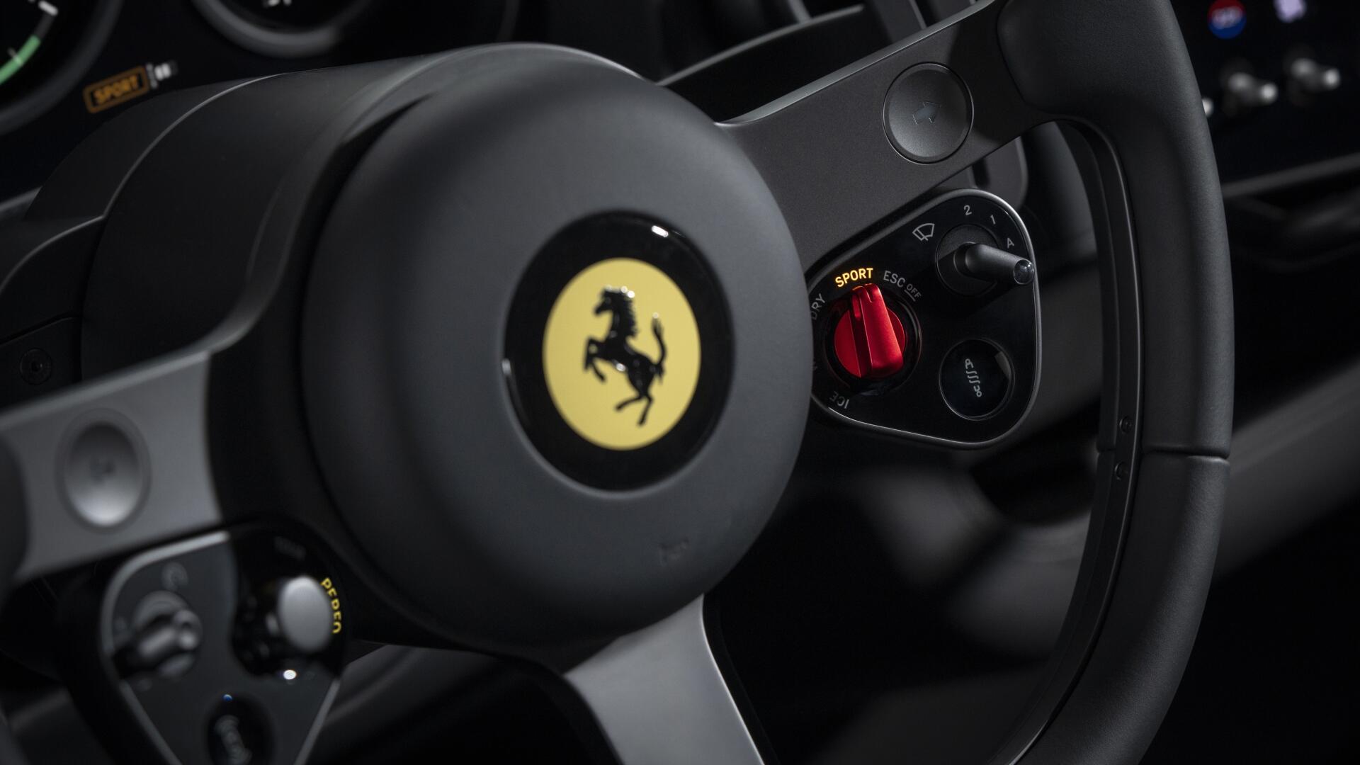 Close-up of Ferrari steering wheel with prancing horse emblem and red drive-mode switch, 4K Ultra HD PC desktop wallpaper showcasing the Ferrari Luce vehicle interior.