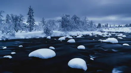 HDR 4K Ultra HD photography of a snowy landscape: ice-covered rocks on a frozen lake beneath a moody sky, a PC desktop wallpaper background.