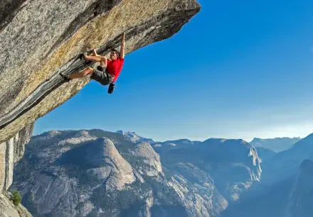 HD PC desktop wallpaper of a climber in red scaling a steep overhang in a sports-climbing shot above a sunlit mountain valley.
