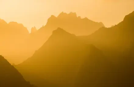 Yellow-hued mountain silhouettes layered in sunlight, serene landscape rendered as 5K Ultra HD PC desktop wallpaper and background.