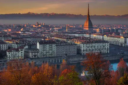 4K Ultra HD PC wallpaper of hazy Turin, Italy cityscape at dusk — Mole Antonelliana rising above riverfront buildings with warm lights and autumn foliage.