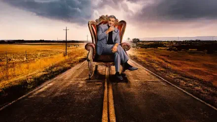 Tulsa King 4K Ultra HD PC desktop wallpaper: a suited man seated in an ornate armchair on a deserted two-lane road, stormy sky and open plains stretching to the horizon.