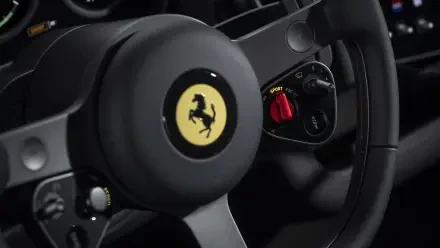 Close-up of Ferrari steering wheel with prancing horse emblem and red drive-mode switch, 4K Ultra HD PC desktop wallpaper showcasing the Ferrari Luce vehicle interior.
