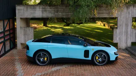 Side profile of a light-blue Ferrari Luce parked beneath a concrete overhang on a brick driveway with sunlit lawn behind — 4K Ultra HD PC desktop wallpaper.