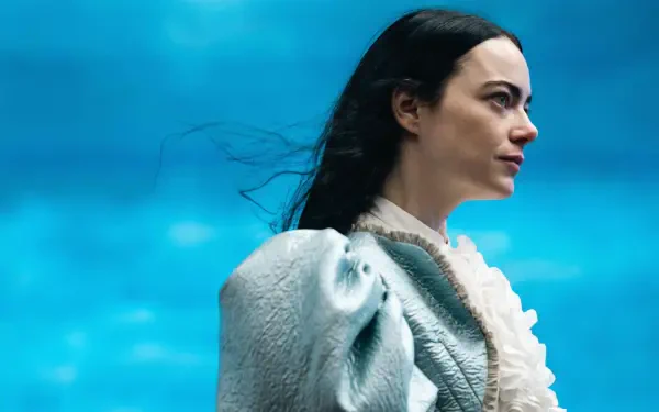 Woman in a pale ruffled period dress and cloak gazes right against a vivid blue sky — Poor Things 4K Ultra HD PC desktop wallpaper.