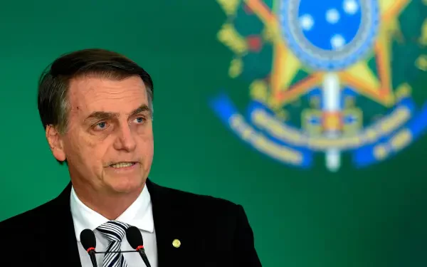 HD desktop wallpaper of a man in a suit and tie speaking at a podium, with the Brazilian national emblem blurred on a green background.