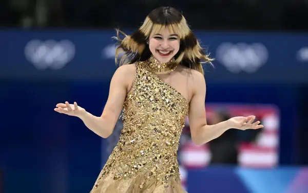 Figure skater in a gold sequined dress smiling during a Winter Olympics routine on the ice — 4K Ultra HD PC desktop wallpaper.