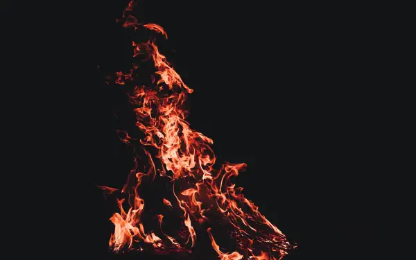 5K Ultra HD PC desktop wallpaper: vivid orange fire and dancing flames rising from a black, shadowed background.