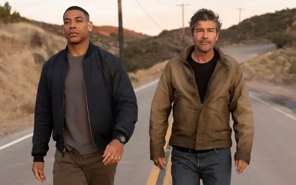 4K Ultra HD PC desktop wallpaper: two men walking along a desert road at dusk, warm lantern glow behind them, cinematic horizon and rugged hills.