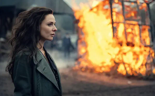 Peaky Blinders: The Immortal Man 8K Ultra HD PC desktop wallpaper and background — woman in coat watches a wooden cart blaze on a smoky street, tense period-drama atmosphere.