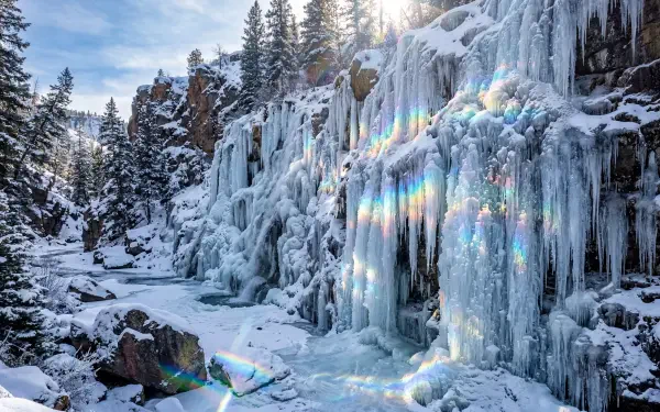 5K Ultra HD PC desktop wallpaper and background: a frozen waterfall with sculpted ice curtains and snow-covered rocks bathed in cold blue light.