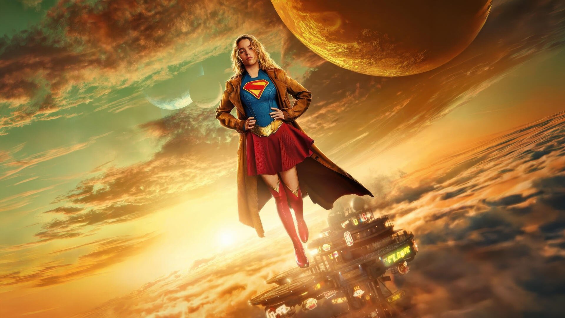 Supergirl (2026) soars above golden clouds toward a distant planet, cape billowing over a futuristic city — 5K Ultra HD PC desktop wallpaper and background.