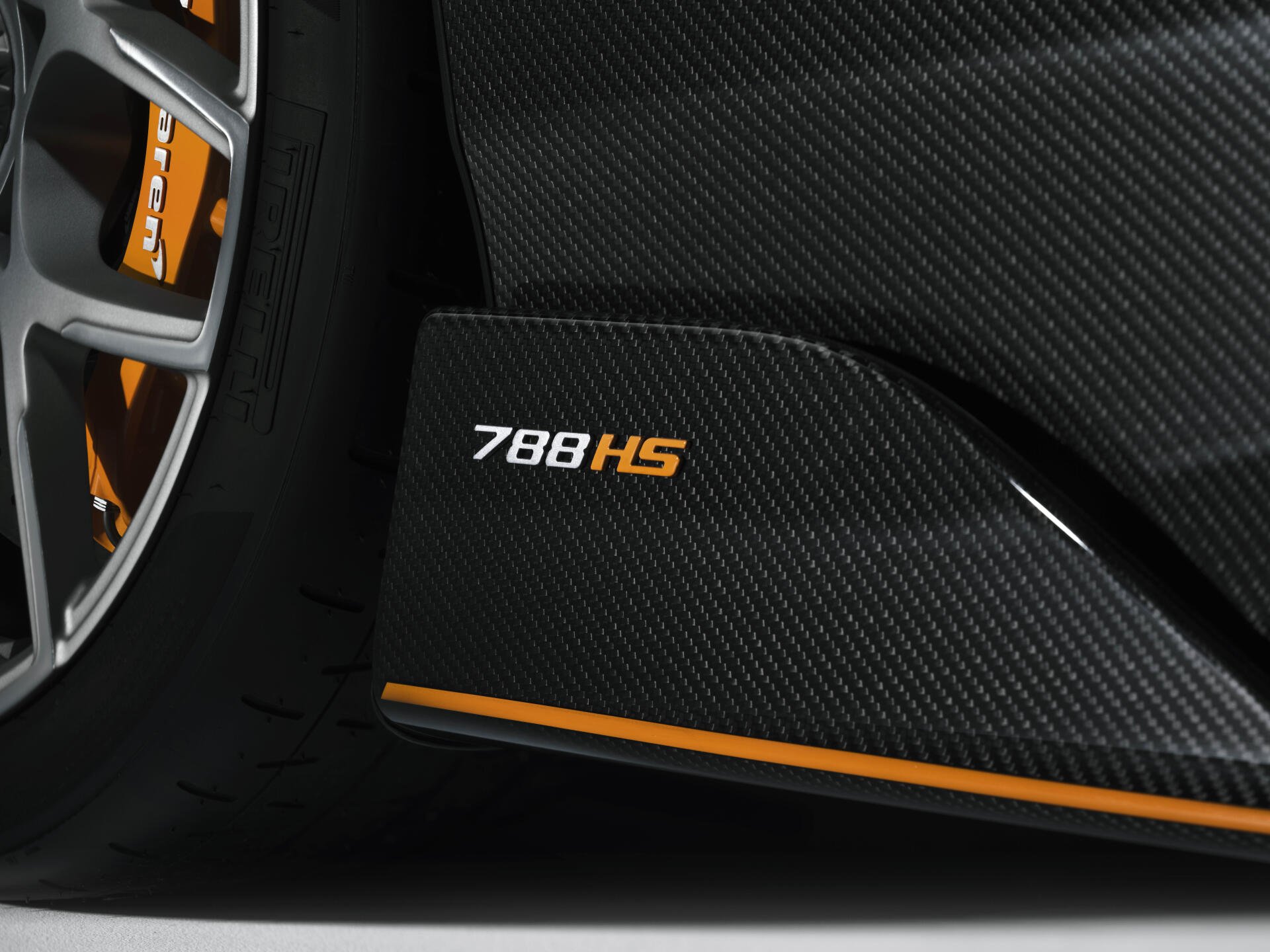 Close-up of McLaren 788HS carbon-fiber side sill and wheel with orange accent stripe — 8K Ultra HD PC desktop wallpaper