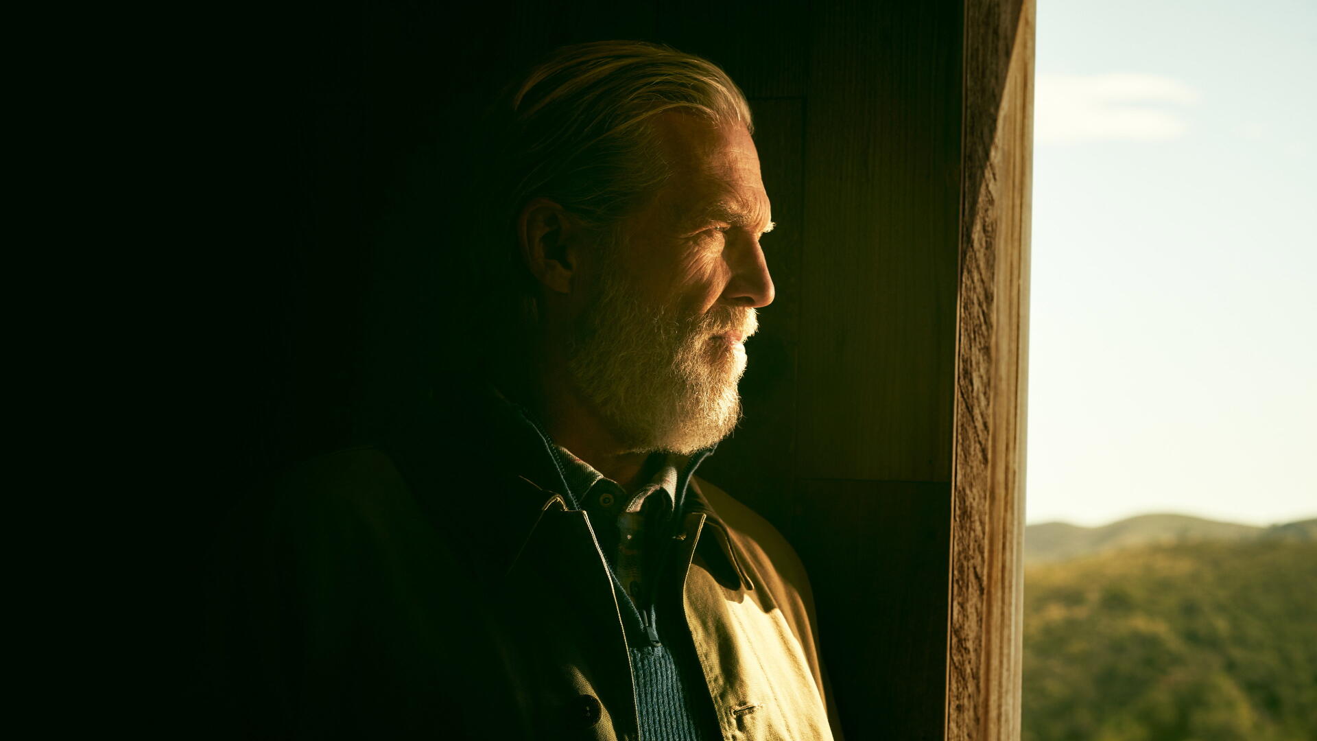 The Old Man — bearded elder in warm window light gazing at sunlit hills; 4K Ultra HD PC desktop wallpaper and background.