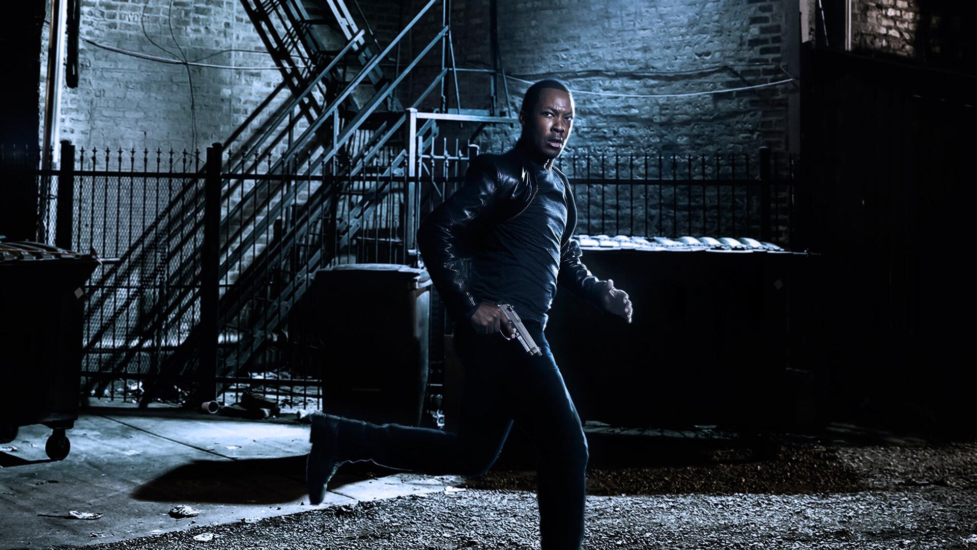 24: Legacy — man in a leather jacket aims a pistol while crouching in a dim, gritty urban alley; 4K Ultra HD PC desktop wallpaper/background.