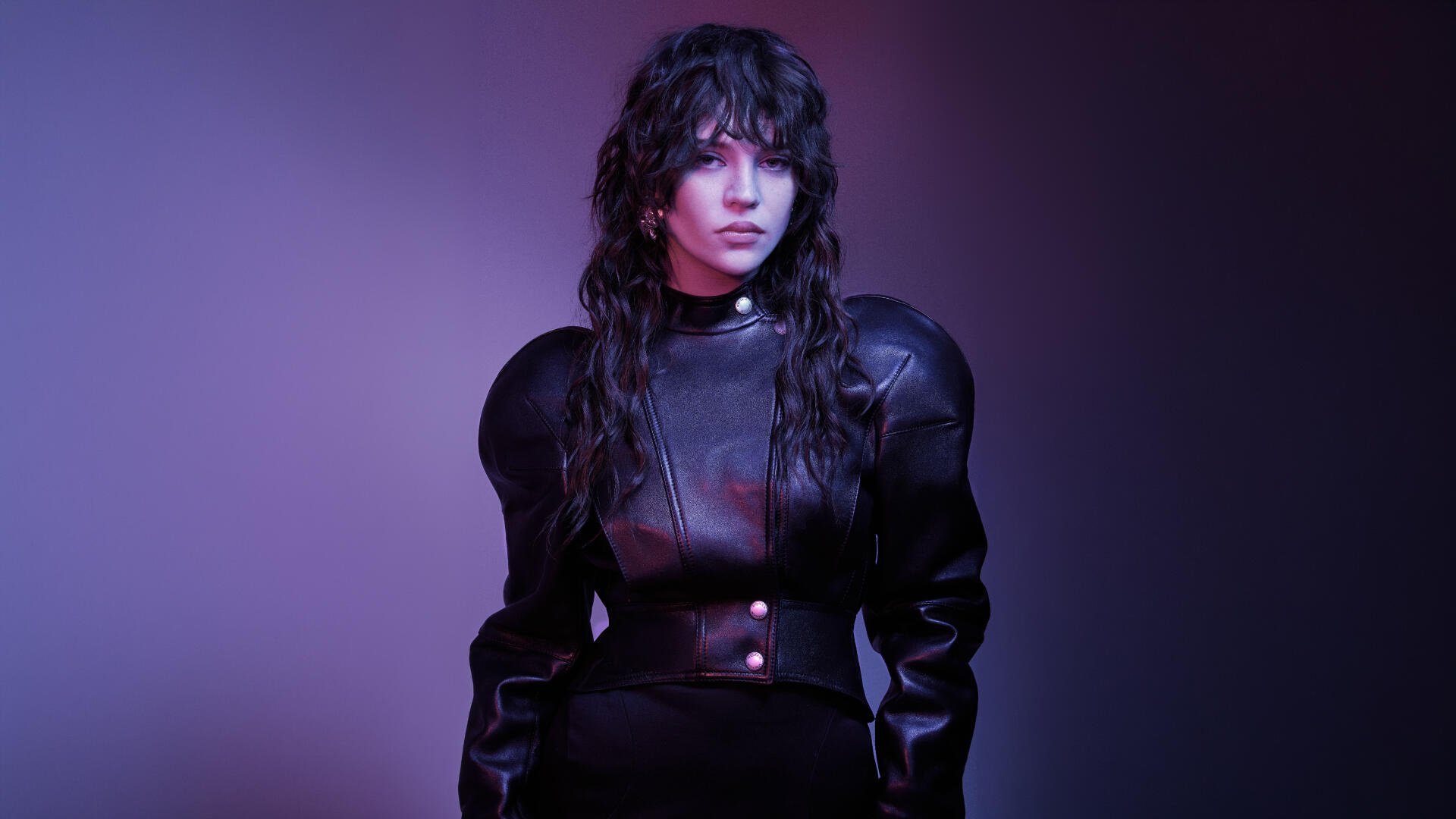 Moody portrait of a young woman in sculpted black outfit with music-inspired styling and purple lighting — 5K Ultra HD PC desktop wallpaper.