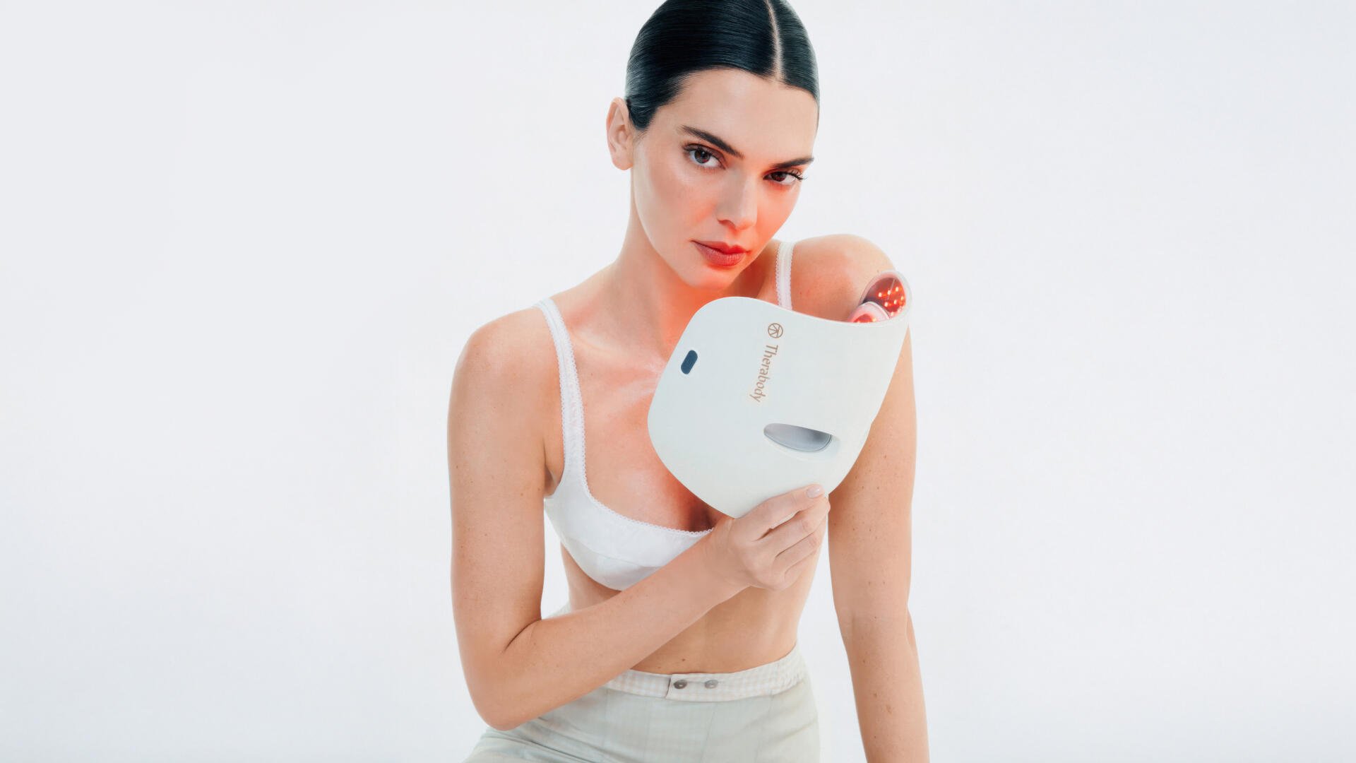 5K Ultra HD PC desktop wallpaper of a poised fashion model in a white crop top holding a sleek white facial mask device against a clean white background.