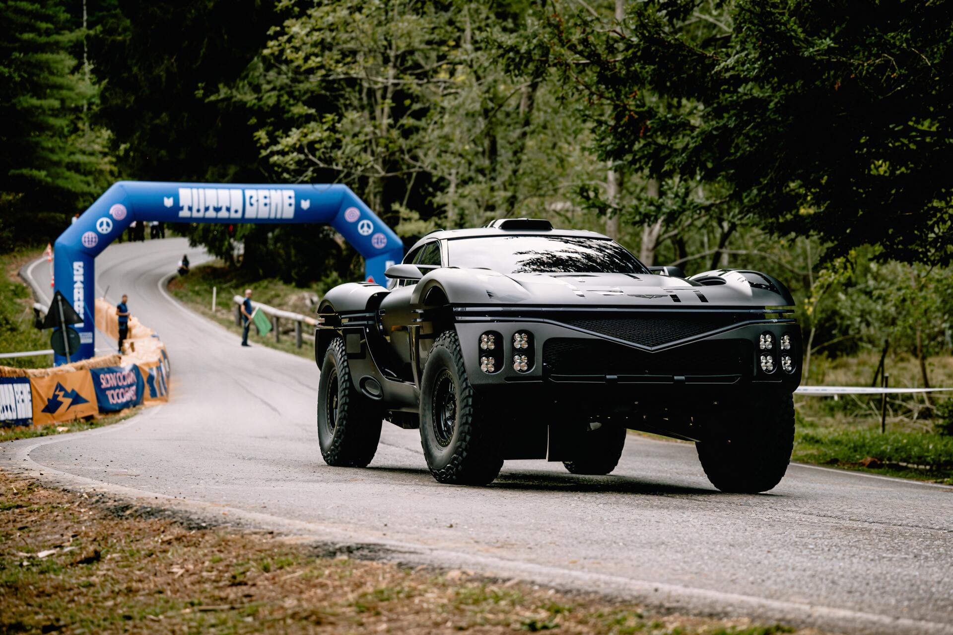 Genesis X Skorpio supercar rally racer on a forest road passing a finish arch, black sports/race car — 4K Ultra HD PC desktop wallpaper background.