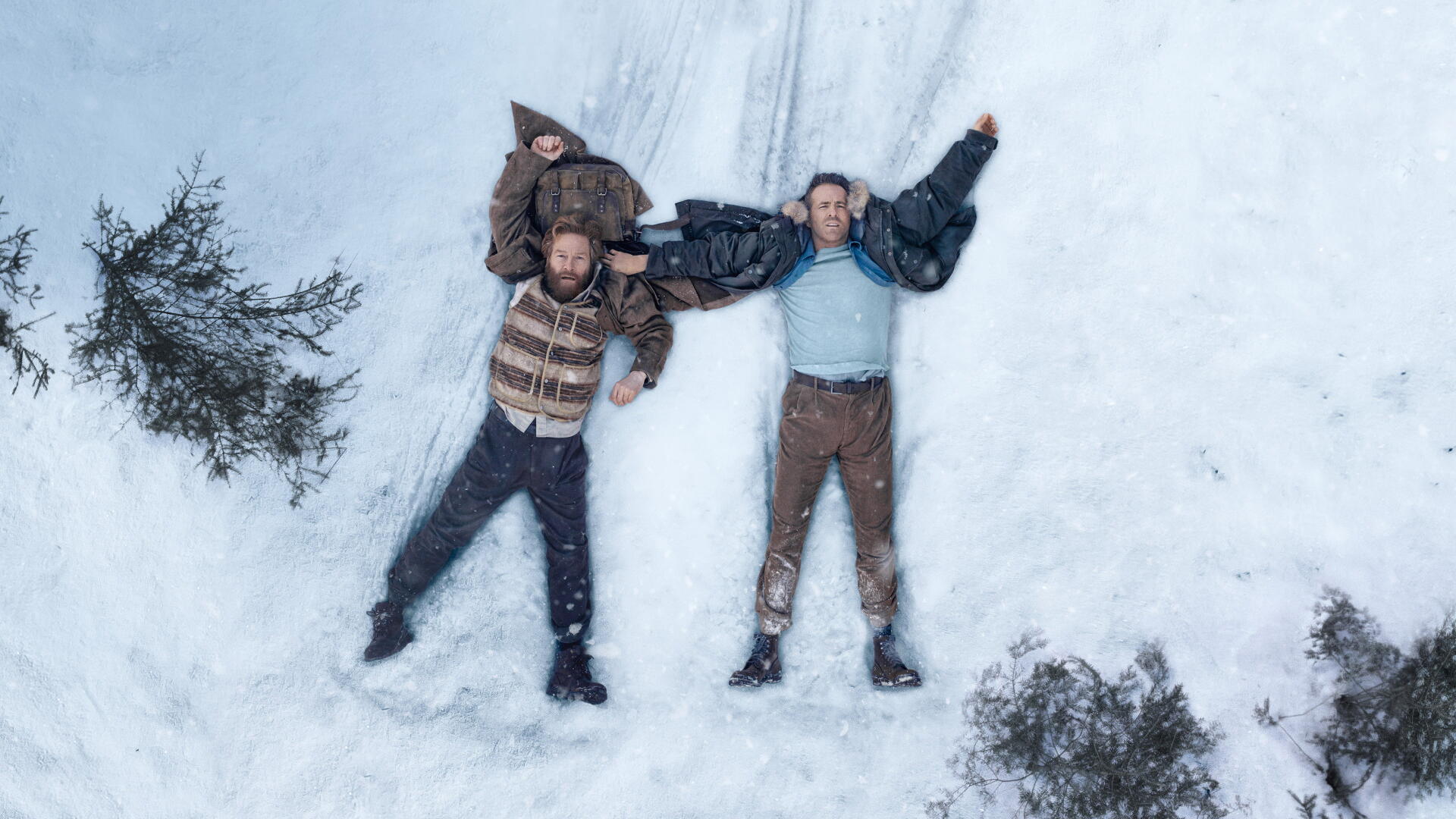 4K Ultra HD PC desktop wallpaper: aerial view of two men lying in snow with arms outstretched, forming a Mayday signal beside scattered pine branches.