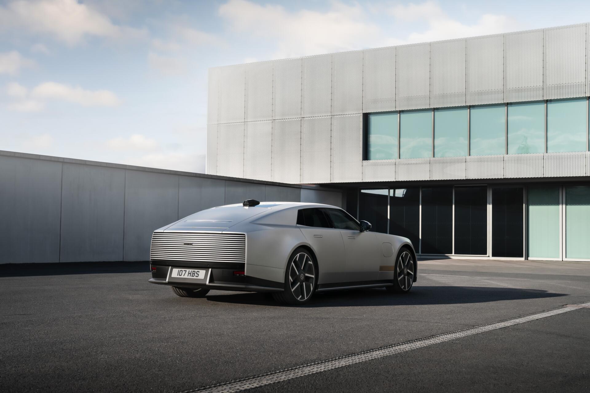 Jaguar Type 01 electric sedan parked outside a modern building, featured in a 5K Ultra HD PC desktop wallpaper.