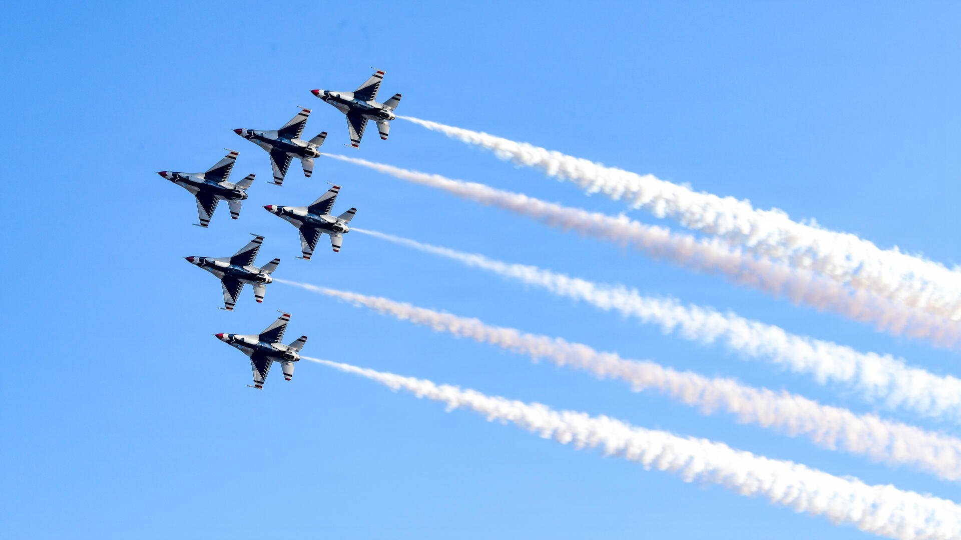 United States Air Force Thunderbirds F-16 Fighting Falcons soar in formation, trailing white smoke across a blue sky in 5K Ultra HD desktop wallpaper.