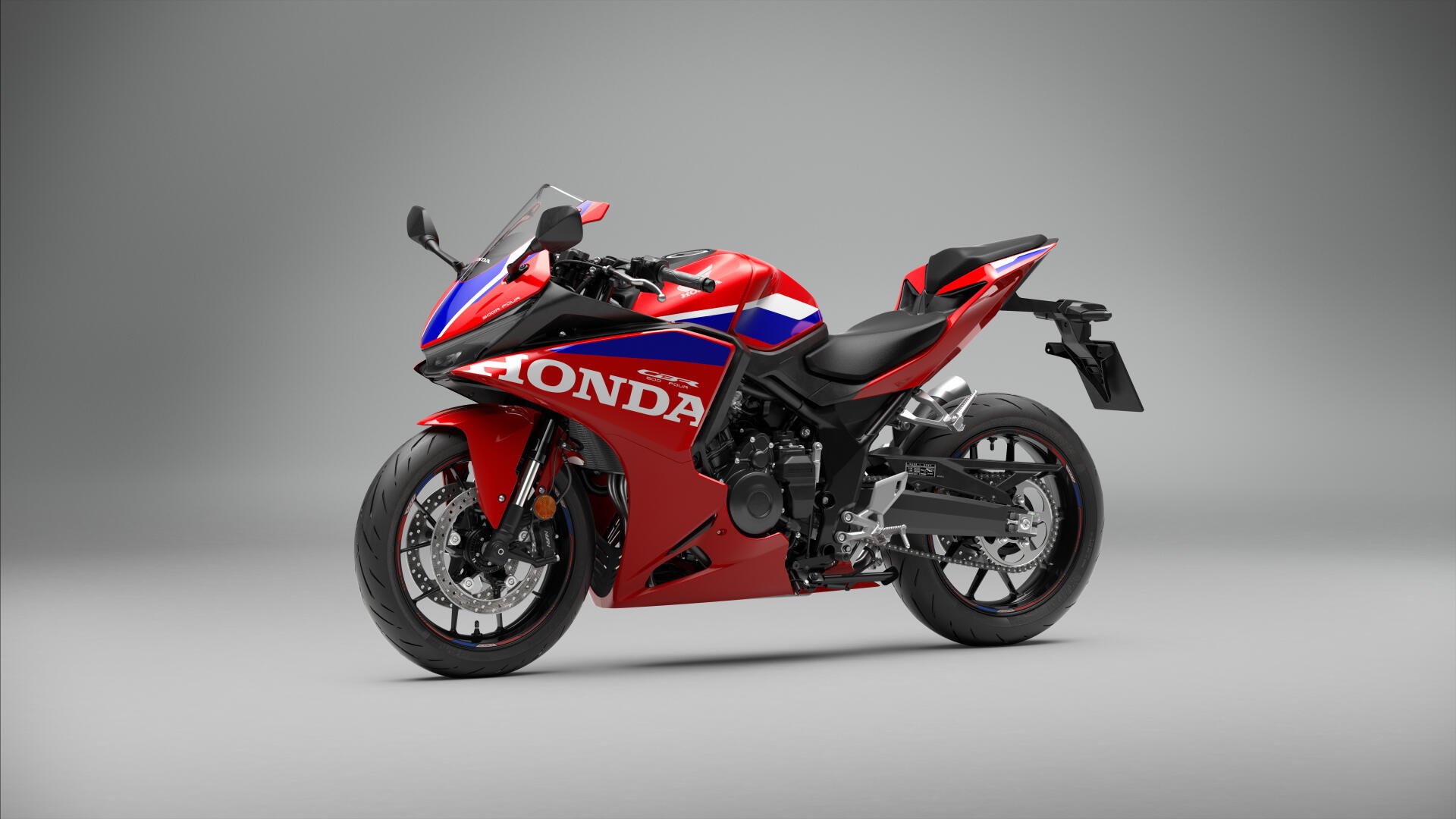 Red Honda CBR500R Four sportbike on a gray studio background, featured in a 5K Ultra HD desktop wallpaper.